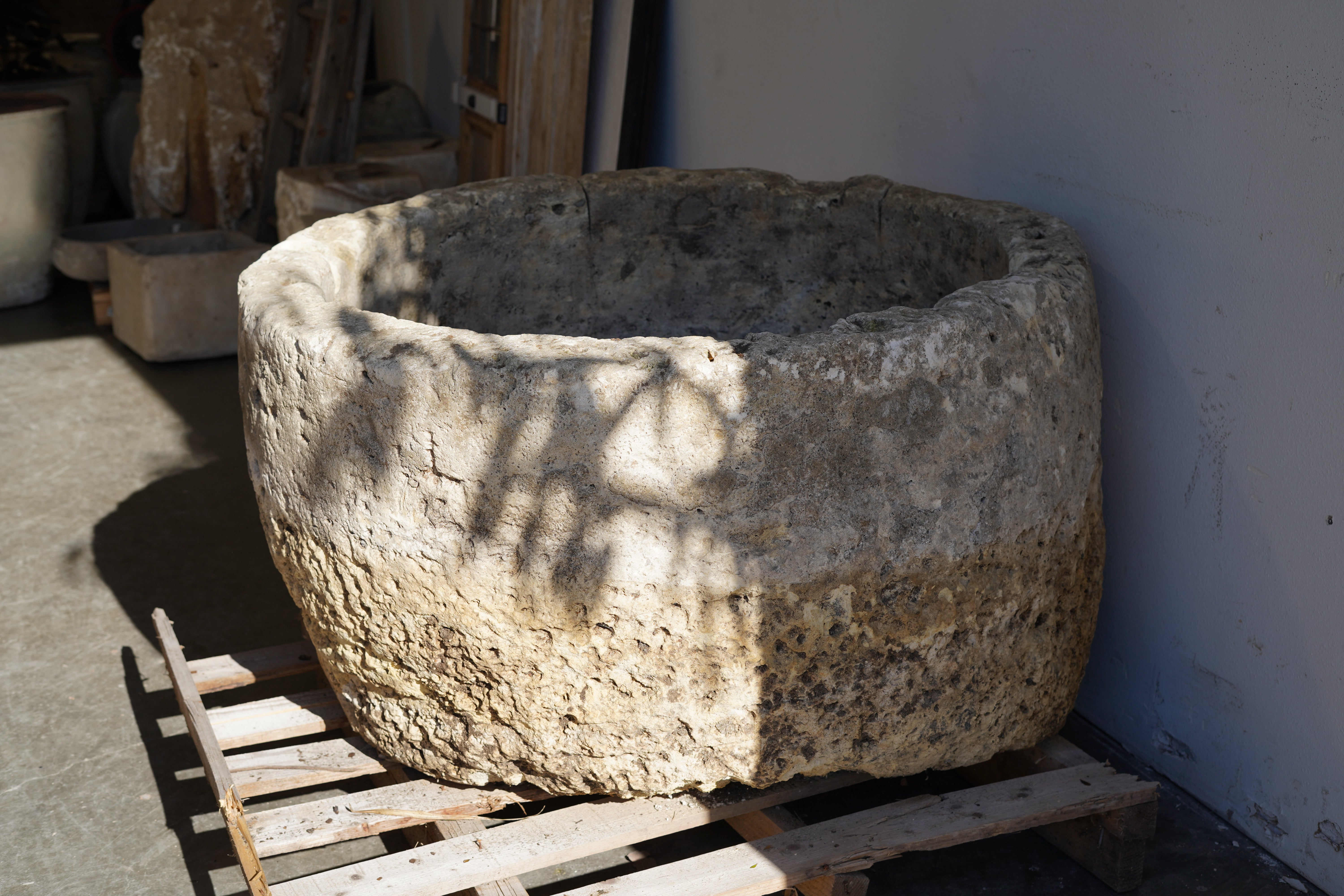 Shadows from leaves on a large hand carved limestone planter.