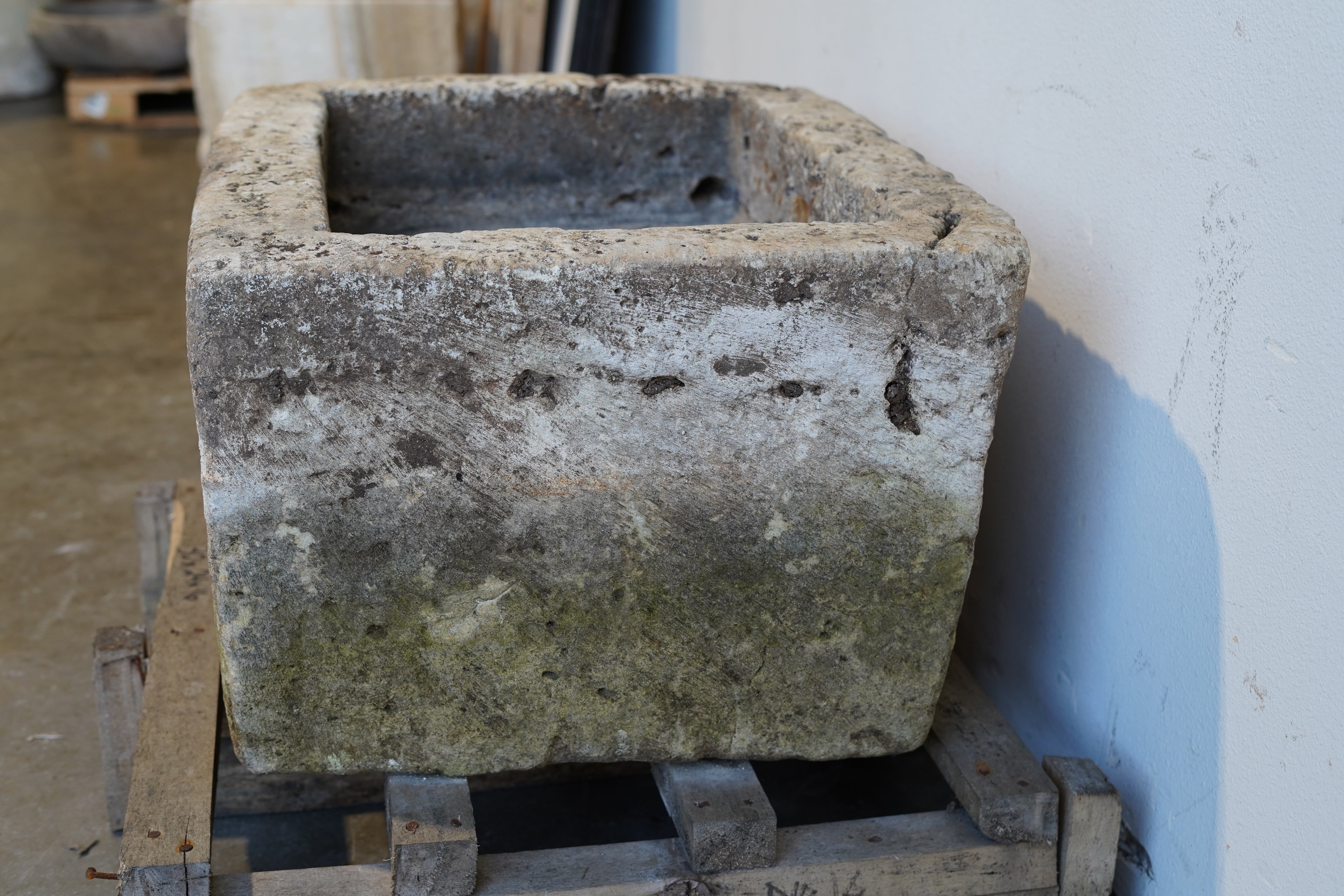 Side view of vintage limestone garden trough, showing thick stone walls and rectangular form with aged patina, hand-carved rectangular design measuring 30L x 24W x 16H inches, perfect for rustic gardens or farmhouse-style interiors.