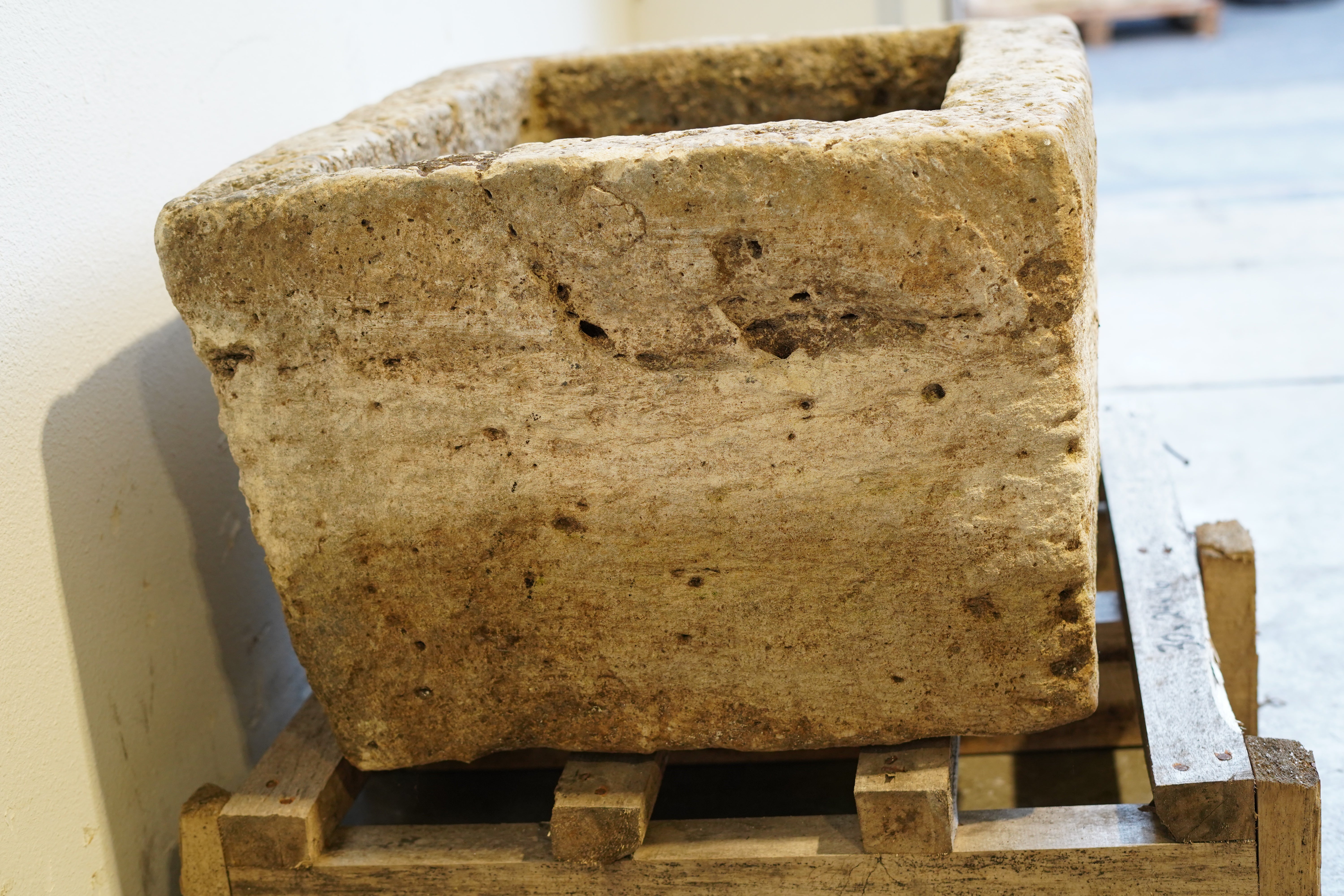Side view of antique limestone trough planter with aged patina, hand-carved rectangular design measuring 30L x 24W x 16H inches, perfect for rustic gardens or farmhouse-style interiors.