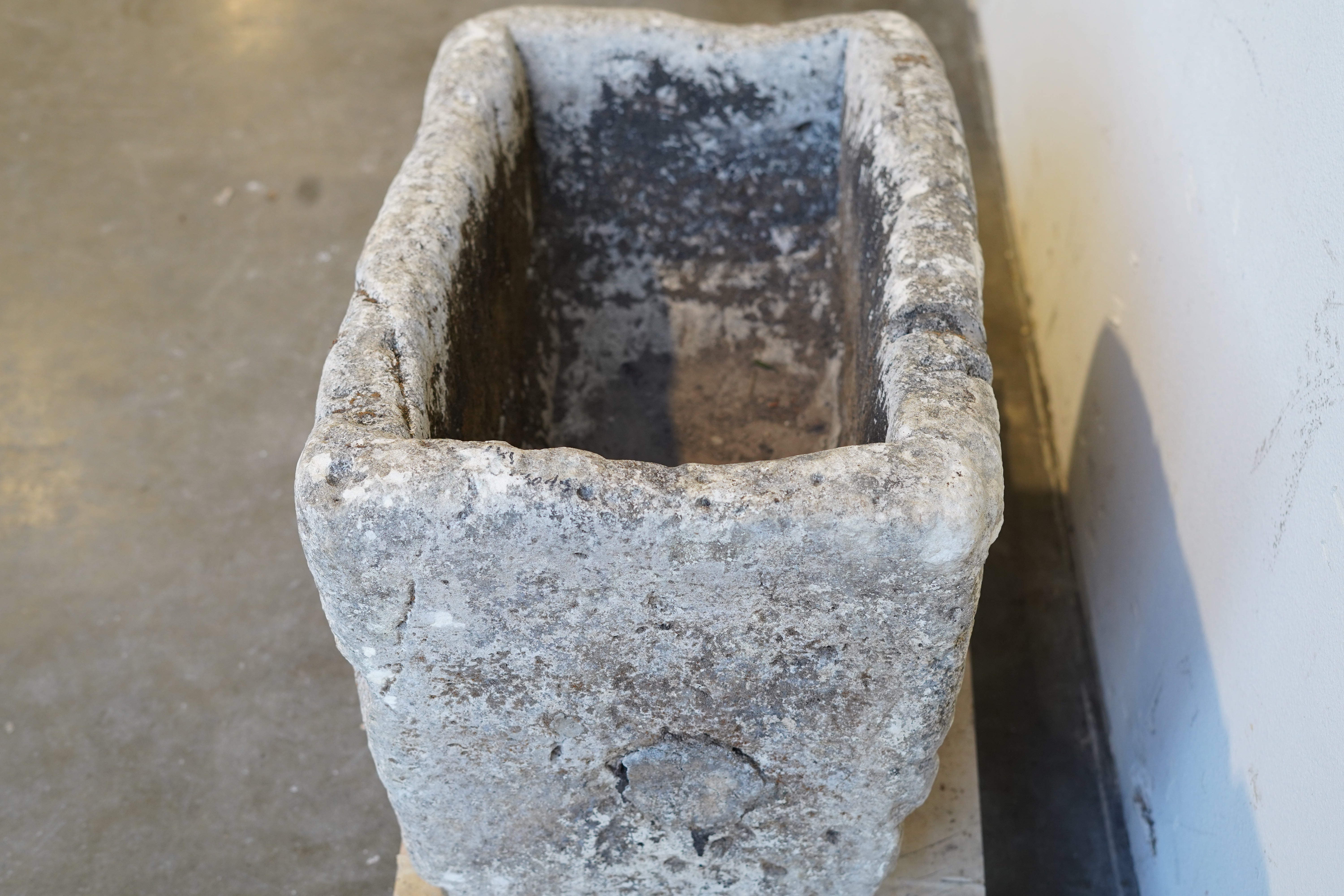 Side profile of vintage limestone trough with rustic surface and moss accents