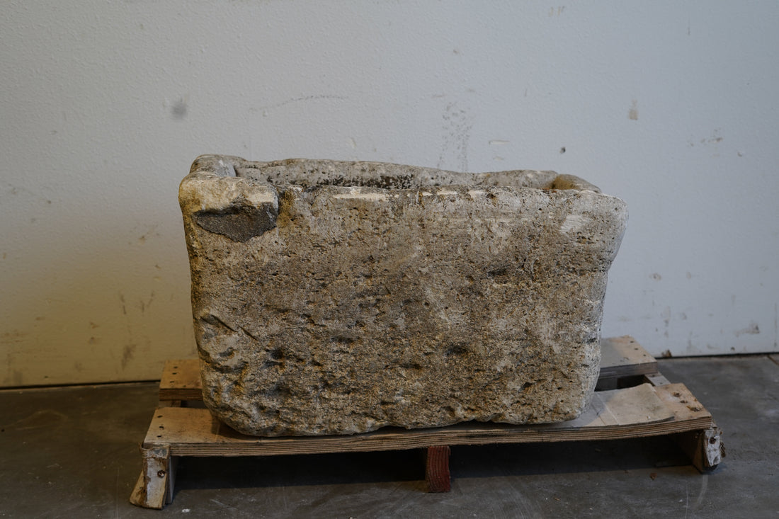 Close-up of antique limestone planter showing carved edges and aged stone details