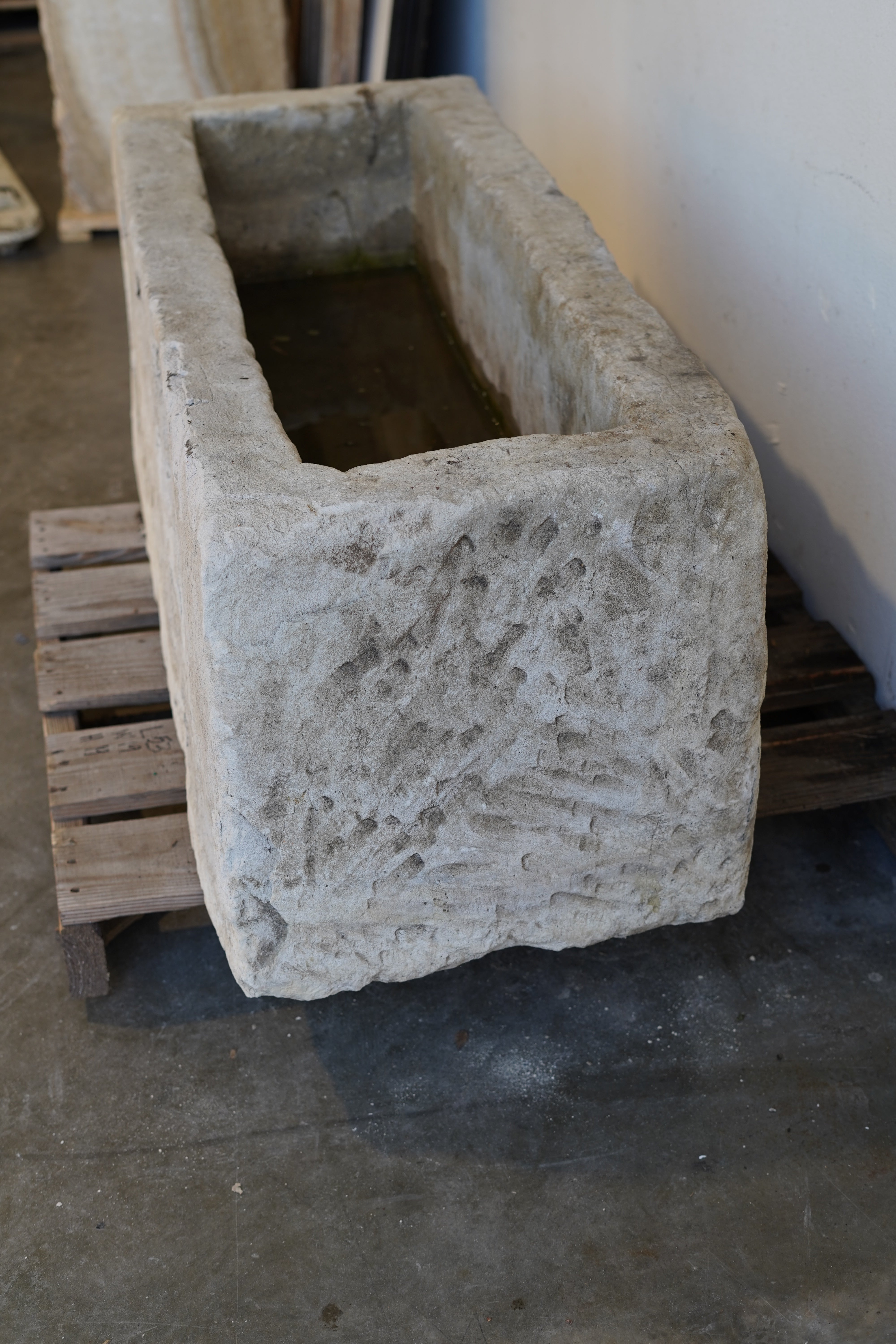 Close-up of aged limestone planter showing weathered texture and carved rim details