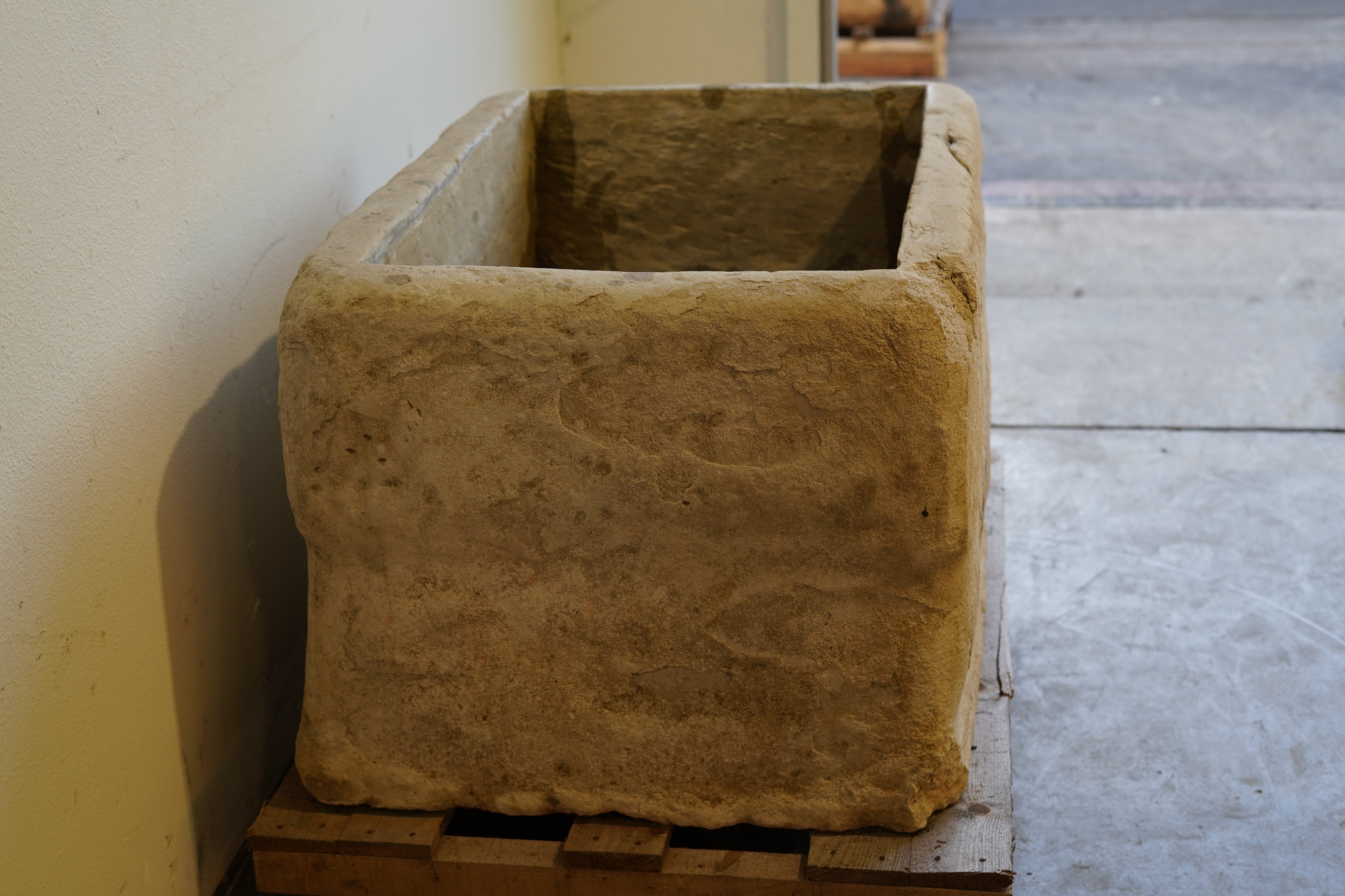 Side view of antique limestone garden trough planter with aged surface and weathered edges.