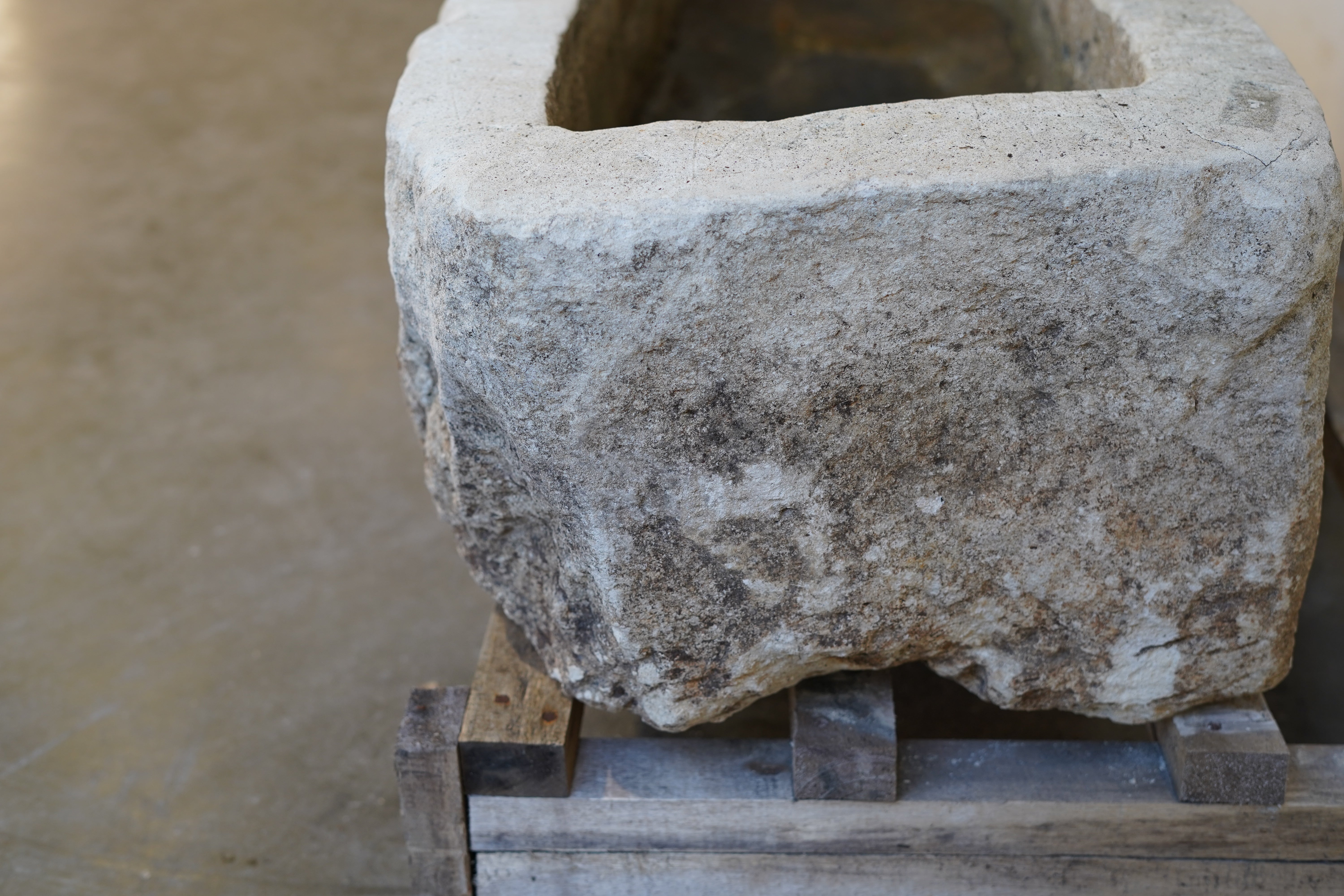 Antique limestone planter, low-profile rectangular shape with weathered texture, angled side view