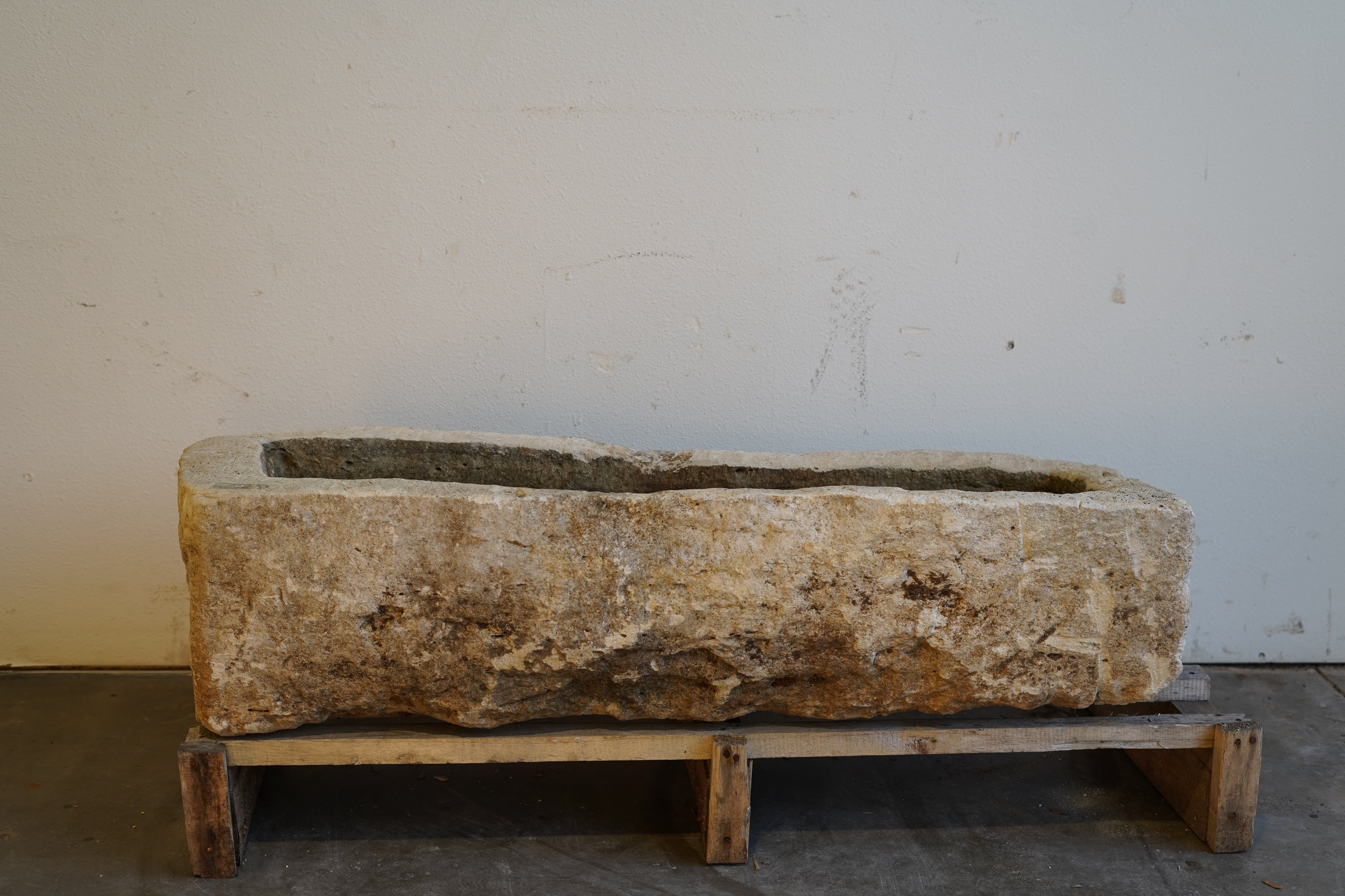 Vintage low rectangular limestone planter with aged patina on stone surface, front angle view.