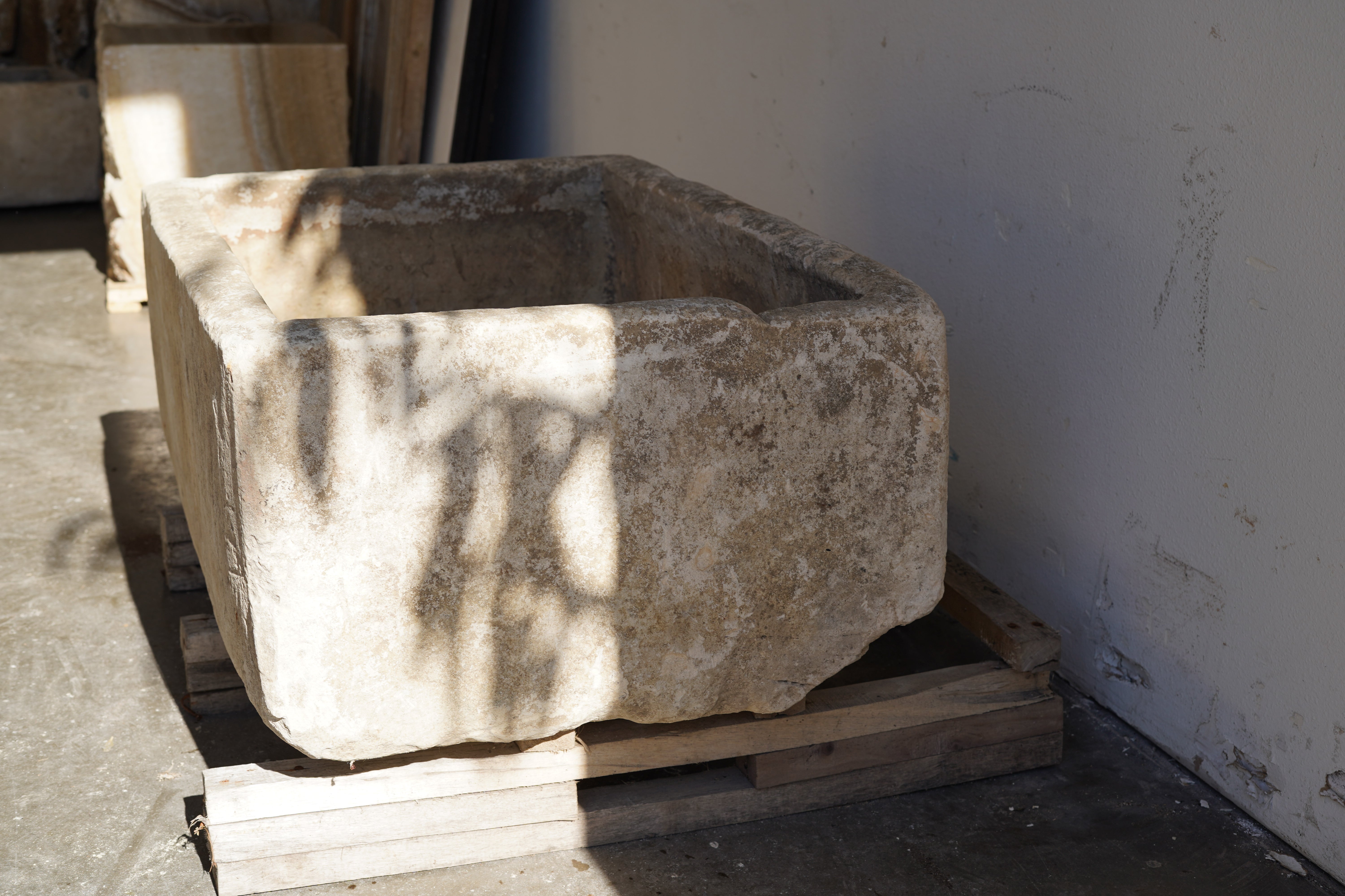 Side view in partial shade of Vintage Limestone Trough in natural lighting. Dimensions: 37.5" L x 25" W x 16.5" H