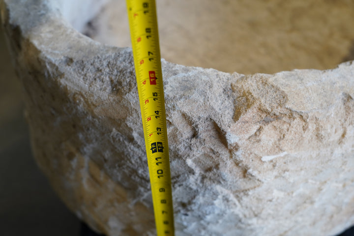 close up side view of vintage hand-carved limestone planter, round shape.